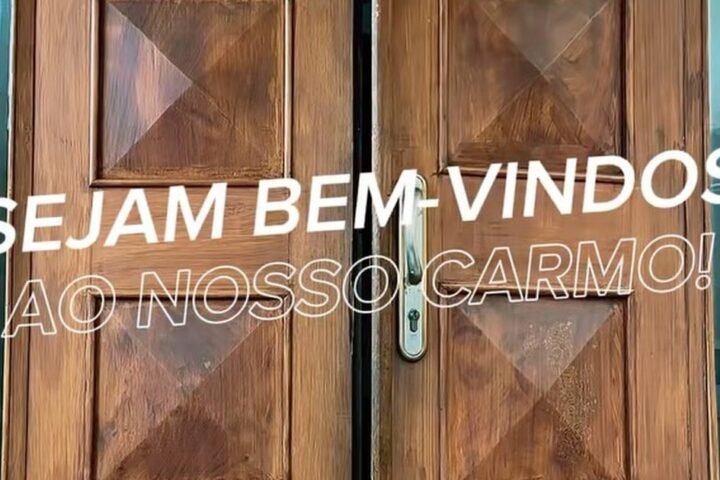 Portas de madeira do Colégio Carmo abertas com a mensagem Sejam bem-vindos ao nosso Carmo, no dia da acolhida do Processo de Admissão 2027
