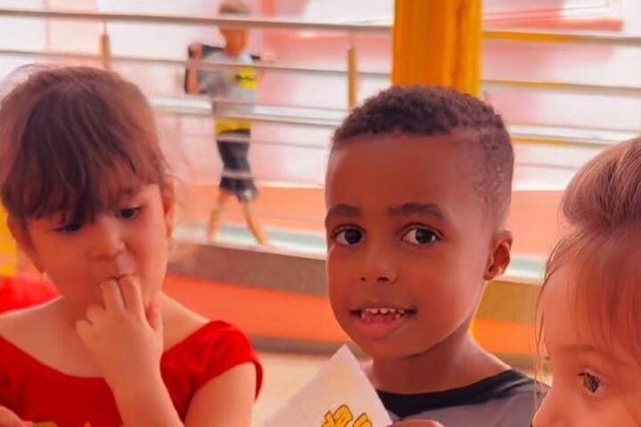 Crianças do Colégio Carmo na abertura da Semana da Criança 2026, uma delas fantasiada de Mulher-Maravilha